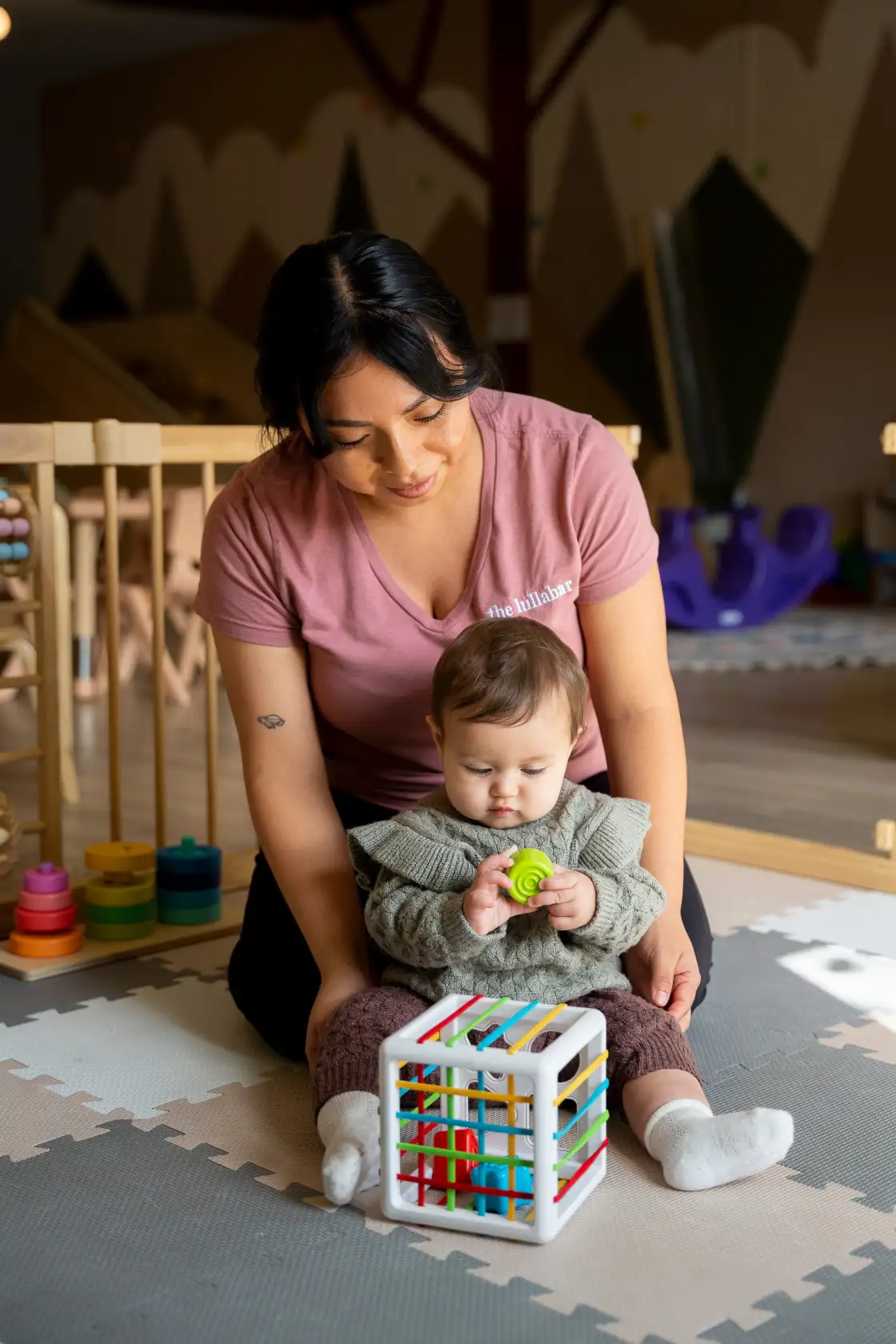 A Lullabar caregiver sitting with a toddler during a childcare session
