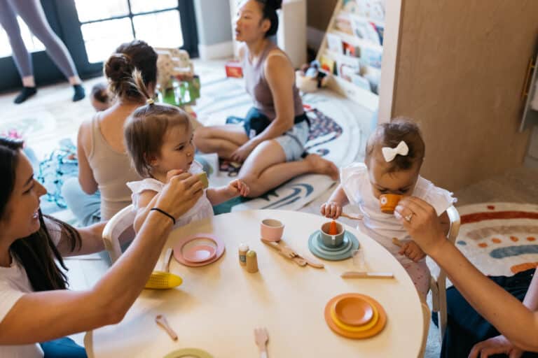 A caregiver sharing a pretend tea party with toddlers